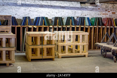 Sheets of glass in many colors, are on display in custom shelves at a glass factory in North America USA Stock Photo
