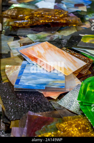 Small pieces of stained glass are piled high at a glass factory, perfect for small glass projects of stained glass mosaics Stock Photo
