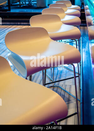 Row of modern bar stools. S shape chairs in front of the counter bar vertical style. Stock Photo