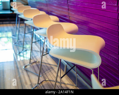 Row of modern bar stools. S shape chairs in front of the counter bar. Stock Photo