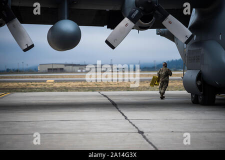 A U.S. Air National Guard 136th Airlift Wing C-130H Hercules crew chief, Naval Air Station Joint Reserve Base Fort Worth, Fort Worth, Texas, secures aircraft chocks for taxi in preparation for an air drop mission over Beller drop zone during Exercise Mobility Guardian 2019, Fairchild Air Force Base, Washington, Sept. 23, 2019. Exercise Mobility Guardian is Air Mobility Command's premier, large scale mobility exercise. Through robust and relevant training, Mobility Guardian improves the readiness and capabilities of Mobility Airmen to deliver rapid global mobility and builds a more lethal and r Stock Photo
