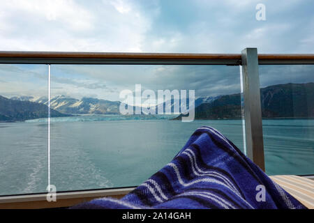 A person sitting on their balcony watching the sailaway on the back of a cruise ship overlooking the Hubbard Glacier. Stock Photo