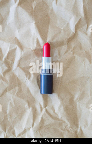 Red liptick on crumpled natural paper background Stock Photo