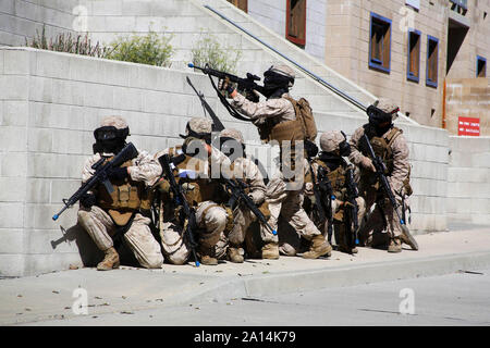 U.S. Marines take cover behind a wall during a training evolution. Stock Photo