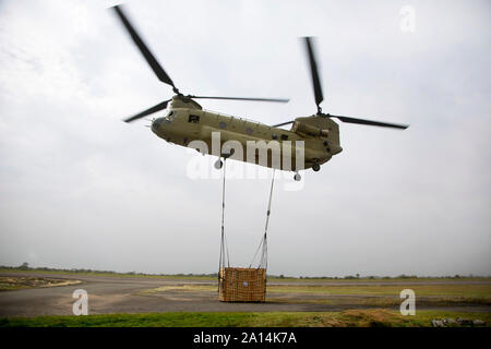A CH-47 Chinook helicopter begins to lift a sling load. Stock Photo