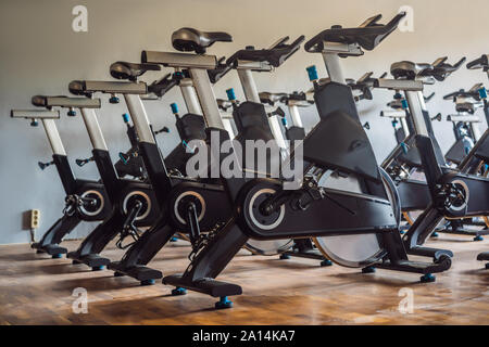 Aerobics spinning exercise bikes gym room with many in a row Stock Photo
