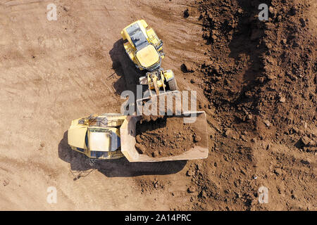 Excavator loading soil onto an Articulated hauler Truck, Top down aerial Stock Photo