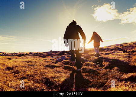 Silhouettes of two hikers walks in sunset light. Trekking concept