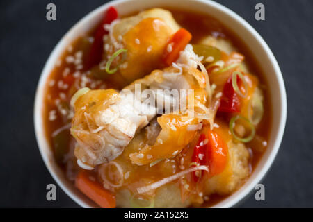 Ray cheeks that have been deep fried in batter and served with a sweet and sour sauce and garnished with finely sliced spring onions and sesame seeds. Stock Photo