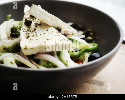 Closeup delicious Greek salad with fresh vegetables and feta cheese with spices and served in clay bowl Stock Photo
