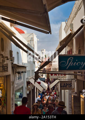 Tourists walking on narrow street in old town of Fira with shops signboards and awnings in Santorini Greece on daytime Stock Photo