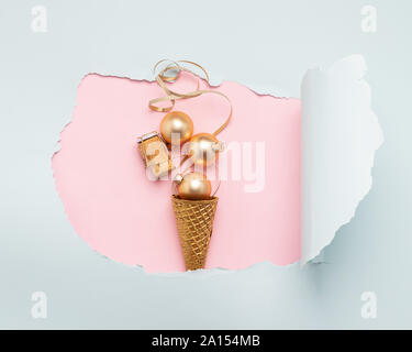 Ice cream waffle cup Christmas balls serpentine cork from a bottle of gold color on a paper hole pink mint color. New Year or Christmas concept. Flat Stock Photo