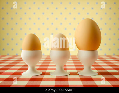 Row of eggs in egg cups with one larger Stock Photo