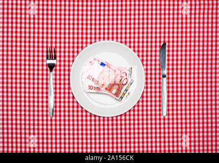Euros banknotes on a white plate with knife and fork overhead view Stock Photo