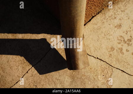 Downpipe at the corner of the building, cracks in the blind area of the house, sunlight and shadow from the drain pipe Stock Photo