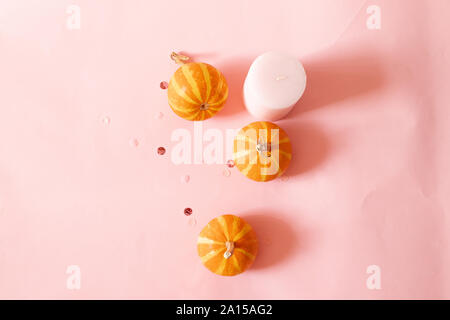 Halloween composition of pink candles, small pumpkins and glitter decor over pink background. Seasonal autumn background Stock Photo