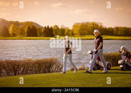Senior couple walking on golf course. Stock Photo