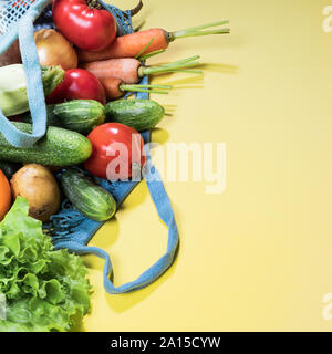 Mesh shopping bag with fresh farm vegetables  on yellow background. Close-up, copy space, square shot. Zero waste, plastic free concept. Eco-friendly Stock Photo