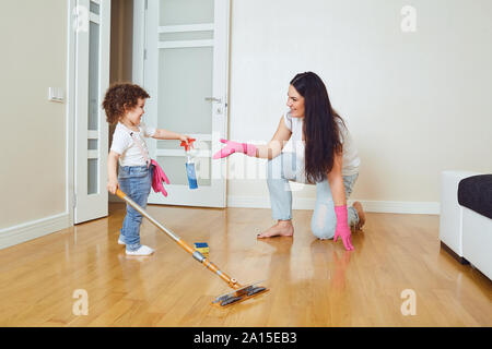 Happy mother and daughter does floor cleaning in the room. Stock Photo