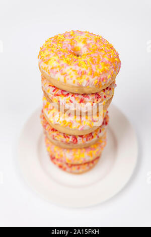 Tower of donuts or doughnuts with colorful frosting or icing and sprinkles on a white plate Stock Photo