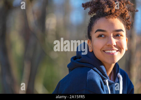 Outdoor portrait of beautiful happy mixed race biracial African American girl teenager female young woman smiling with perfect teeth wearing a blue ho Stock Photo