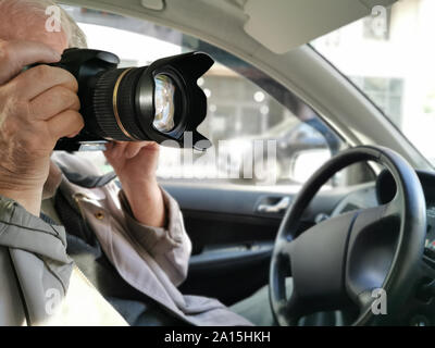Private investigator with digital camera making photographs in car closeup Stock Photo