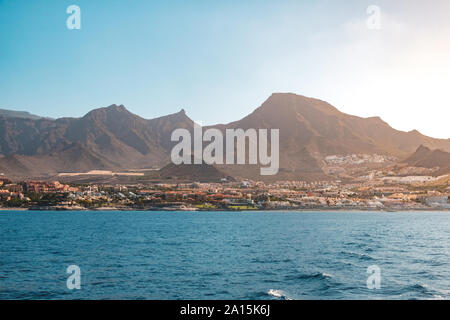 ocean view on shore with hotels and city and scenic mountain background - Coast of Tenerife -