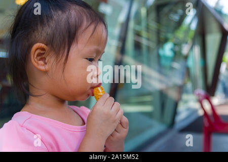 Adorable asian child smiling and enjoy eating breaded sticks at restaurant in her lunch.  High resolution image gallery. Stock Photo