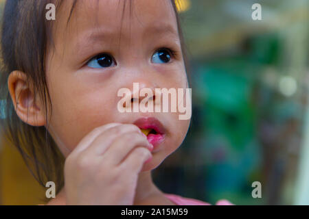 Adorable asian child smiling and enjoy eating breaded sticks at restaurant in her lunch.  High resolution image gallery. Stock Photo