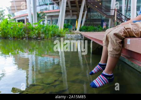 Little kids look at the water and feeding fishs on the wooden bridge.  High resolution image gallery. Stock Photo