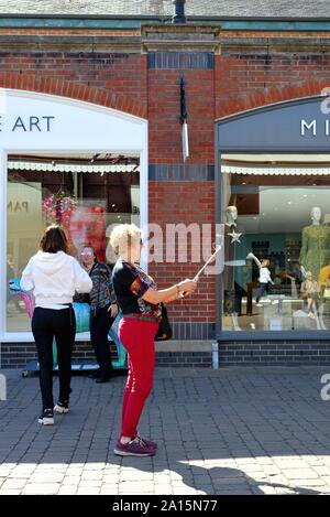 A middle aged woman taking a selfie of herself outside a retail shop in Windsor Berkshire England UK Stock Photo