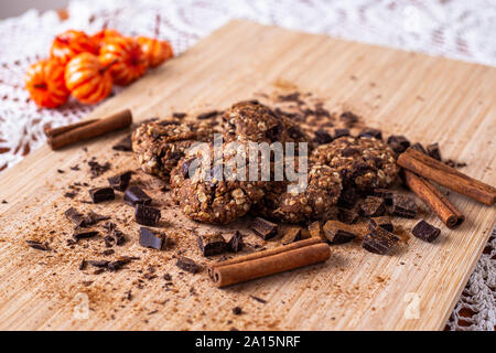Chocolate cookies on wooden table with cinnamon sticks. Autumn style food photo with pumpkin. Stock Photo