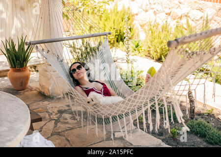 Young woman lying in a hammock with a dog Stock Photo