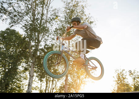 Young man jumping with BMX bike at sunset