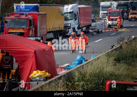 Germany. 24th Sep, 2019. Two firefighters in protective suits walk past the scene of the accident. In the accident with four trucks on the Autobahn 2 between Peine and Braunschweig a dangerous substance escaped. According to police, two people were seriously injured and a dangerous goods transporter was also involved. Credit: Sina Schuldt/dpa/Alamy Live News Stock Photo
