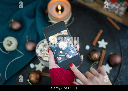 Woman's hand taking picture of cup of Hot Chocolate with marshmellows with smartphone Stock Photo