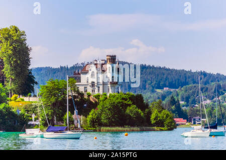 Sailboats moored at lake by church in Woerthersee against sky Stock Photo