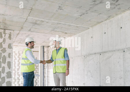 Two workers shaking hands construction site Stock Photo