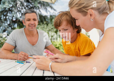 Father, mother and son doing homework together on terrace Stock Photo