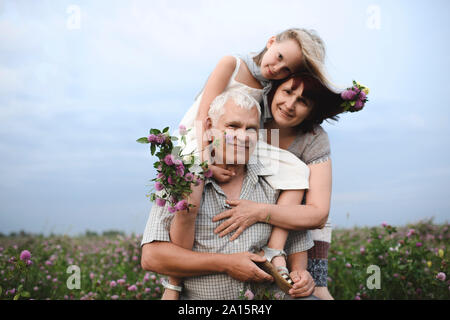 Portrait of little girl and her grandparents with picked flowers in nature