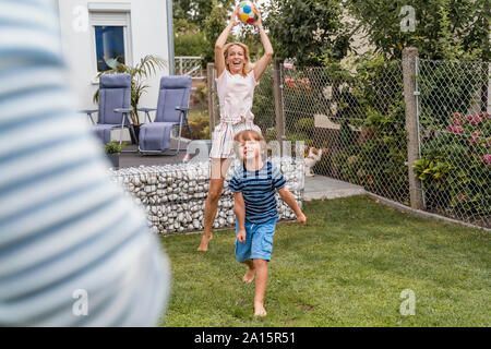 Happy family playing football in garden Stock Photo