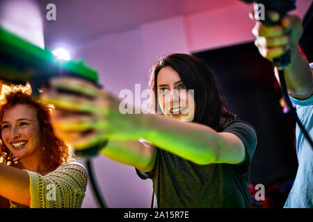 Friends playing and shooting with pistols in an amusement arcade Stock Photo