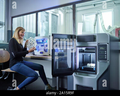 Female technician checking turbine wheel being printed with 3D printer Stock Photo
