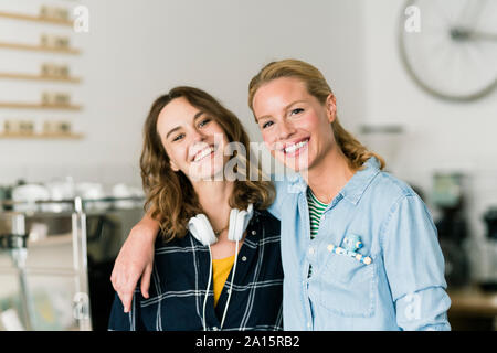 Two young women standing proud in their own coffee shop Stock Photo