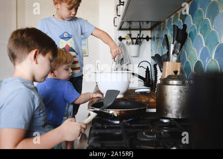 Three brothers cooking pancakes in the kitchen Stock Photo