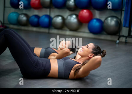 Twin sisters training in gym doing sit-ups Stock Photo