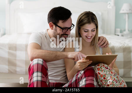 Young attractive couple using tablet in bedroom Stock Photo