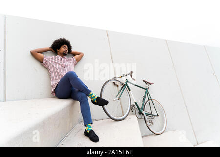 Young man during break leaning on a wall, bicycle Stock Photo
