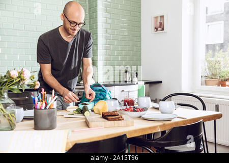 Man in a kitchen packing snacks for lunch break Stock Photo