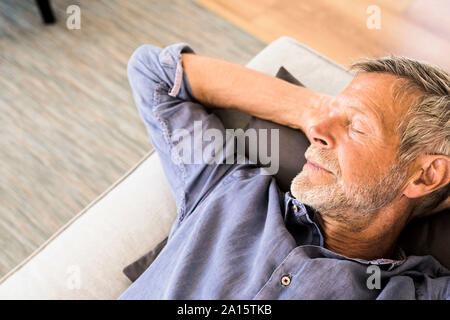 Senior man lying on couch at home taking a nap Stock Photo